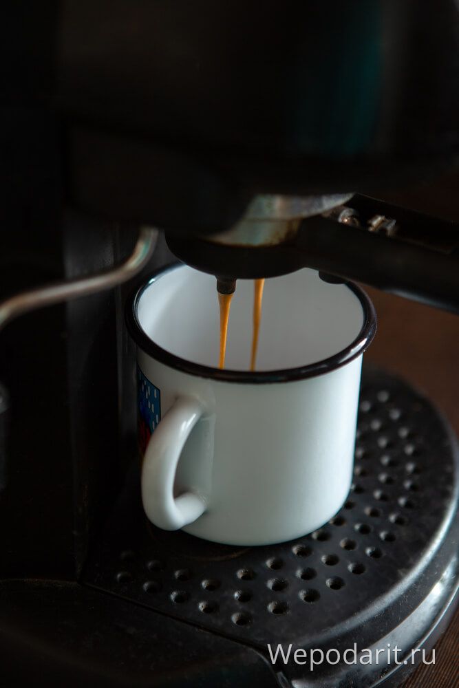 чорна кавоварка наливає каву в кружку