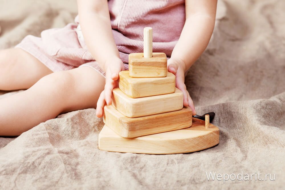 дівчинка 2 роки грає з дерев'яною пірамідкою