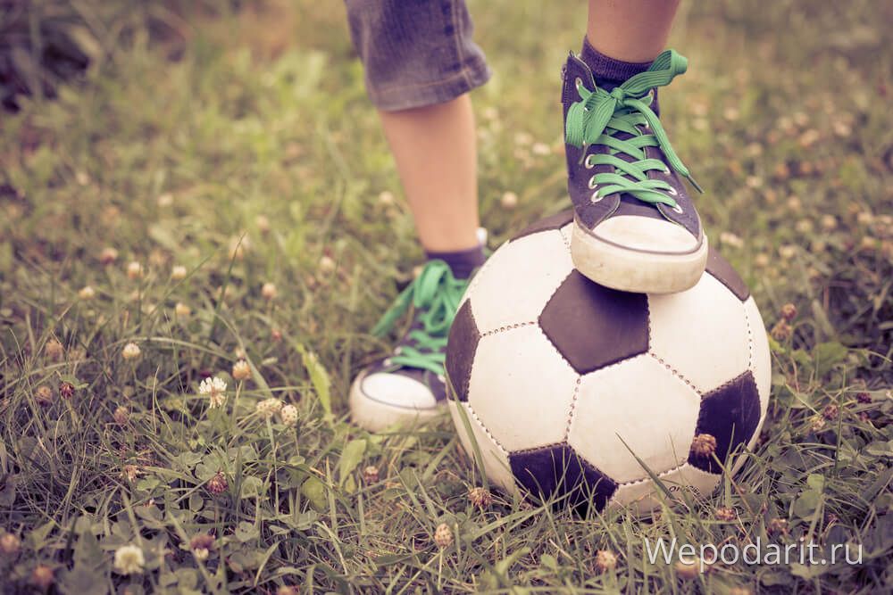 хлопчик 6 років поклав ногу на футбольний м'яч