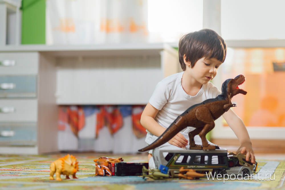 хлопчик грається з іграшковими динозаврами