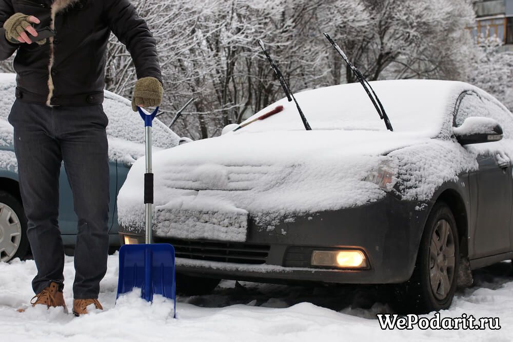 чоловік чистить автомобіль від снігу