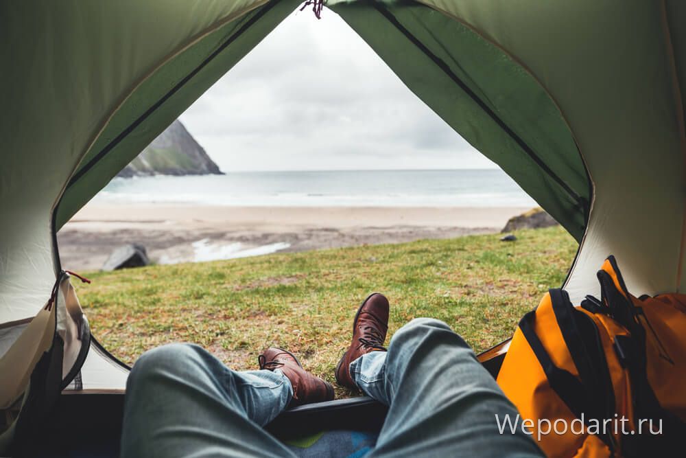 мужчина лежит в палатке с видом на океан