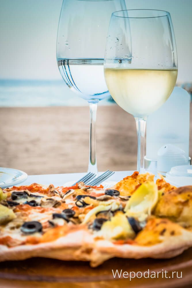 піца і 2 келихи вина на березі моря